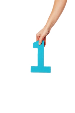 Female hand holding up the number 1 against a white background conceptual of numbers, measurement, amount, quantity, accounting and mathematicsの写真素材