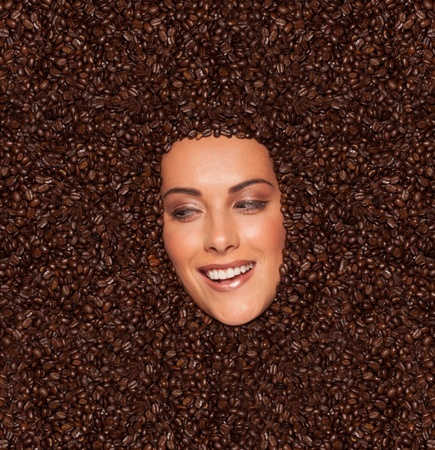 The face of an attractive, smiling woman completely surrounded by a background of rich, coffee beensの写真素材
