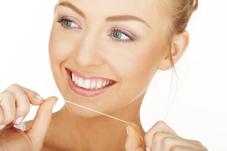 Sexy woman on white cleaning her teeth 