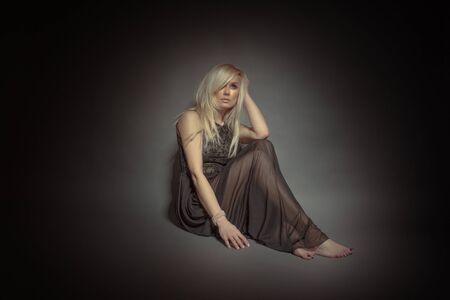 Sitting blonde dressed in a see through brown gownの写真素材