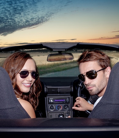 Happy smiling couple in a convertible car. People outdoors.Sunsetの写真素材