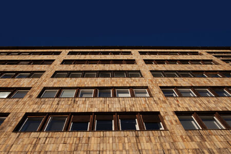 Low angle view looking up of the exterior facade of a stylish modern apartment or office block with multiple rows of windowsの写真素材