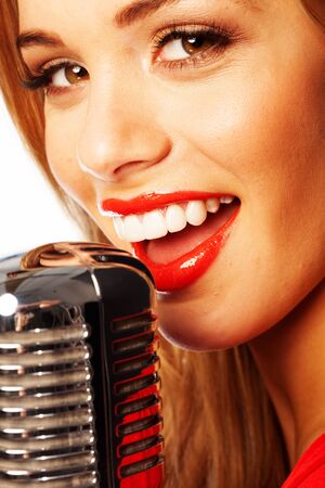 Close up portrait of a beautiful young female vocalist wearing bright red lipstick singing into a microphoneの写真素材