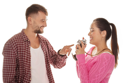Laughing man pointing to a camera in his wifes hands as they relax and have fun while preparinge to take a photograph as a memento of their vacation isolated on whiteの写真素材