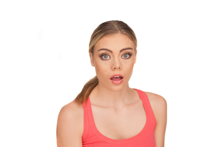 Portrait of a shocked blond woman with an open mouth and eyes wide open wearing a red tank top on a white backgroundの写真素材