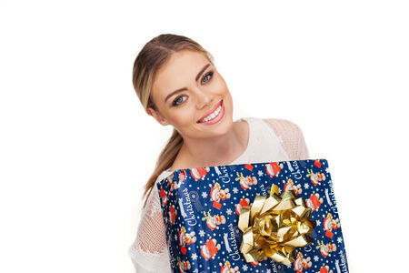 Young woman holds a gift wrapped in christmas paper, isolated on whiteの写真素材