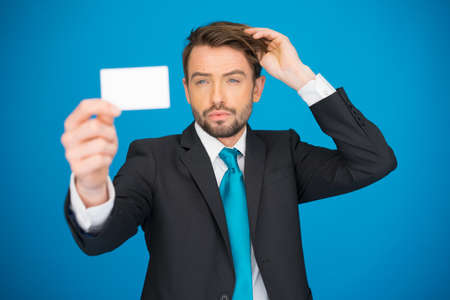 handsome businessman showing blank business card on blueの写真素材