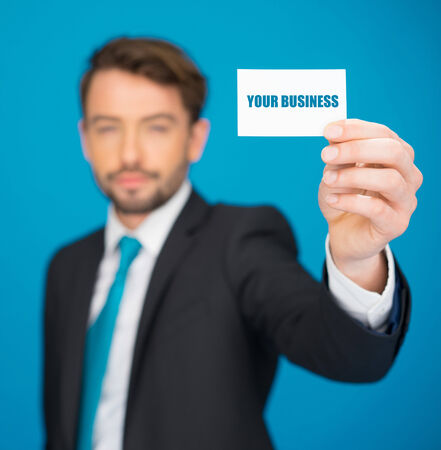 handsome businessman showing blank business card on blueの写真素材