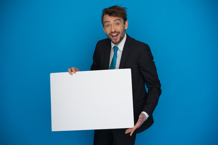 Businessman holding blank poster on blueの写真素材
