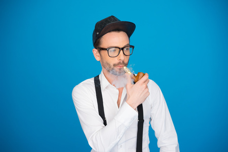 man wearing shirt and hat smoking e-pipe wearing hatの写真素材