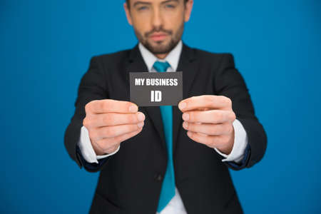 handsome businessman showing blank business card on blueの写真素材