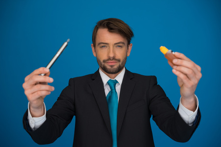 businessman topping up his e-cigarette with e-liquid on blue background