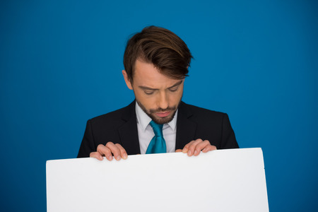 Businessman holding blank poster on blueの写真素材