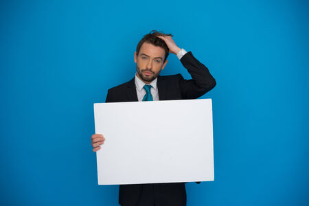Businessman holding blank poster on blueの写真素材