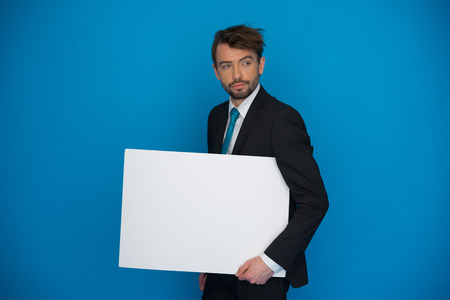 Businessman holding blank poster on blueの写真素材