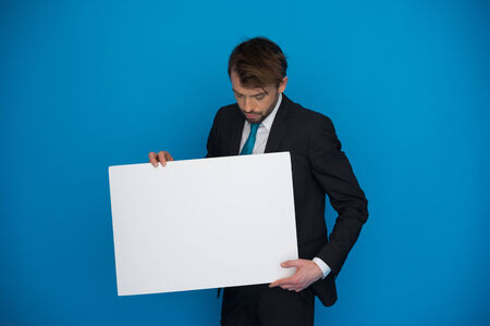 Businessman holding blank poster on blueの写真素材