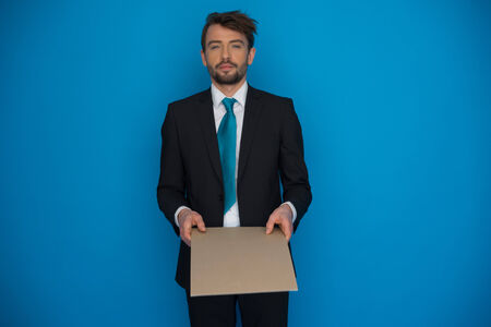 Businessman holding blank poster on blueの写真素材