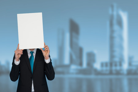 Businessman holding blank poster in a city backgroundの写真素材