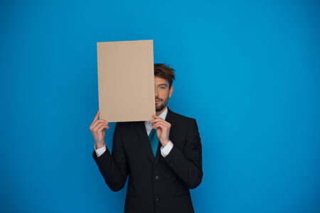 Businessman holding blank poster on blueの写真素材