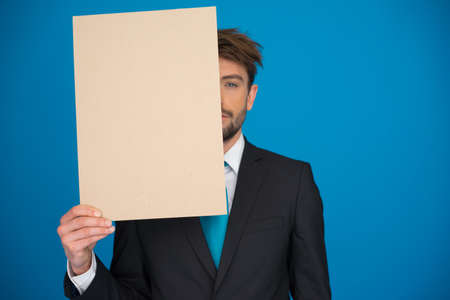 handsome Businessman holding blank poster on blueの写真素材