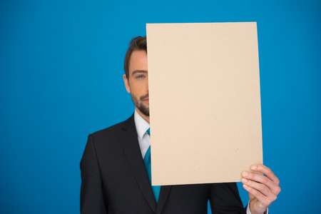 handsome Businessman holding blank poster on blueの写真素材