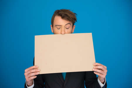 handsome Businessman holding blank poster on blueの写真素材