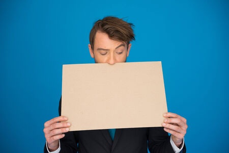 handsome Businessman holding blank poster on blueの写真素材