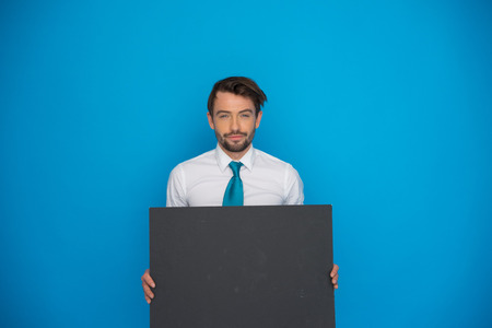 Businessman holding blank black poster on blueの写真素材