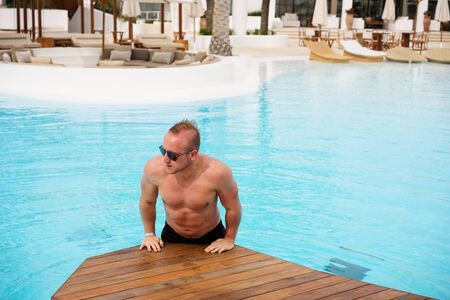 man jumping out of the water near residence with swimming pool