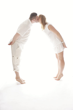 Lovely Couple Wearing All White Clothes Kissing While in Tiptoe.の写真素材