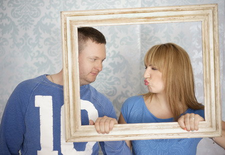 Loving couple in picture frame. Beautiful young couple looking at each smilingの写真素材