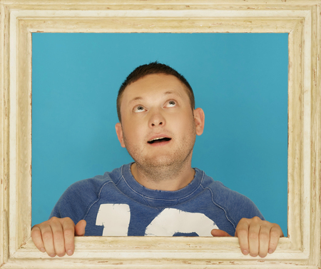 Young Man Inside Wooden Picture Frame Thinking of Something.の写真素材
