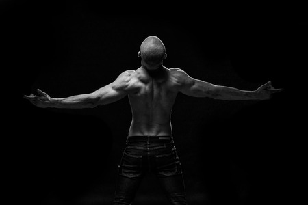 Close up of sports man's muscular back isolated on black backgroundの写真素材