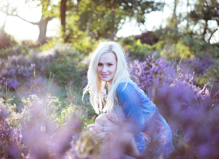 Beautiful blonde woman on the lavender field wearing jeans jacket .の写真素材