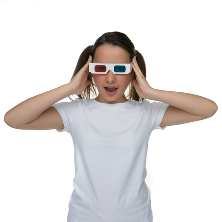 Young girl with her hair in pigtails wearing 3d stereoscopic glasses, ioslated on whiteの写真素材