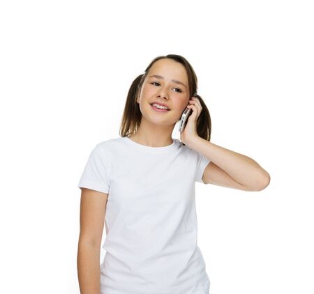 Happy young girl with her hair in pigtails listening to a call on her mobile with a smile, on whiteの写真素材
