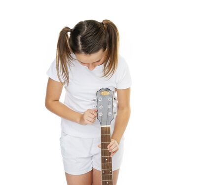 Girl in pigtails tuning guitar on white backgroundの写真素材