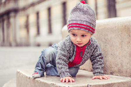 happy little baby boy wearing hat in the city