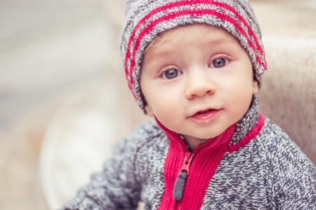 portrait of happy little baby boy wearing hat in the city