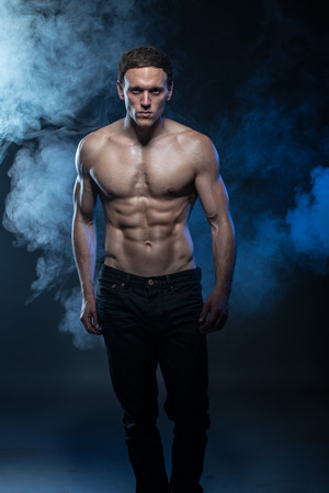 Portrait of a muscular male model against dark background with smoke. cat walkの写真素材