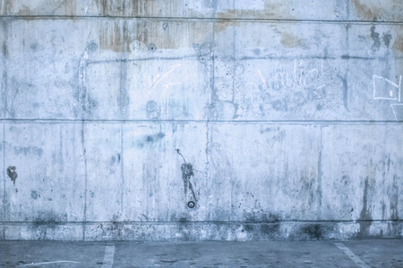 Empty commercial parking garage with a grunge concrete brick wall, overhead lighting and pillars with empty baysの写真素材