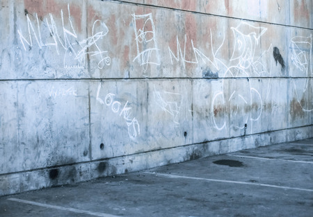 Empty commercial parking garage with a grunge concrete brick wall, overhead lighting and pillars with empty baysの写真素材