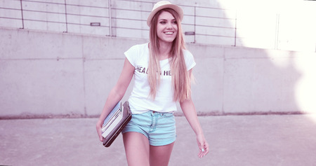 Attractive trendy young female student walking along with the books happyの写真素材