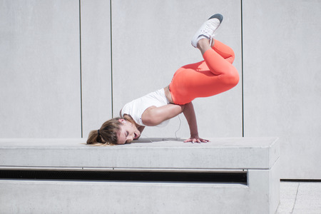 Active Pretty Young Female Dancer Doing a Hip Hop Dance Pose on White Benchの写真素材
