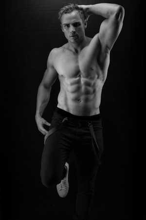 Muscular handsome sexy guy posing on blackの写真素材