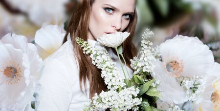 Beautiful portrait of a young woman surrounded by the flowersの写真素材