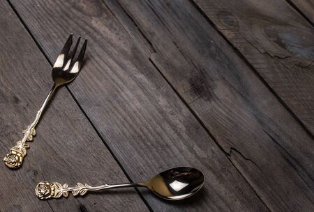 golden and silver vintage forks and spoons on old wooden tableの写真素材