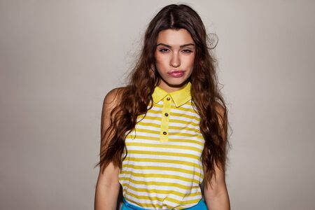 pretty brunette model wearing yellow top and blue skirt posingの写真素材