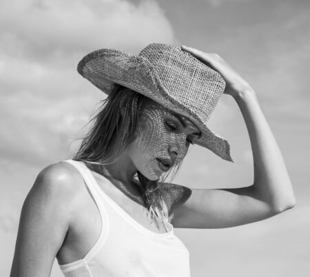 Portrait of beautiful young woman with straw hat on a sunny day  over sky and trees landscape. Black and white photo - face closeup of pretty girl with straw hat pattern shadow on her faceの写真素材