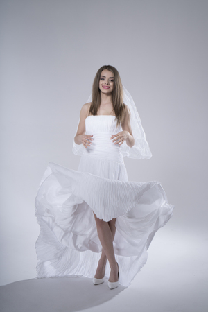 Happy sexy beautiful bride brunette girl in white wedding dress on white backgroundの写真素材